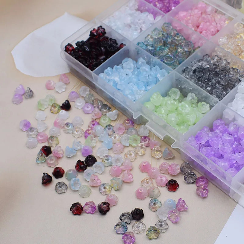 A collection of colorful glass beads in various shades including purple, pink, blue, and clear, arranged in small plastic com