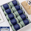 A box of YEDAN MERIN worsted wool thread yarn balls in green and blue colors for knitting projects.