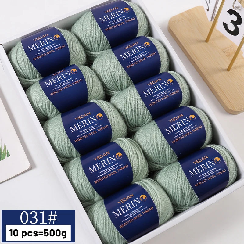 A box of YEDAN MERIN worsted wool thread yarn balls in green and blue colors for knitting projects.