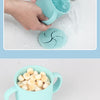 A light blue silicone snack cup with a lid is being rinsed under running water.