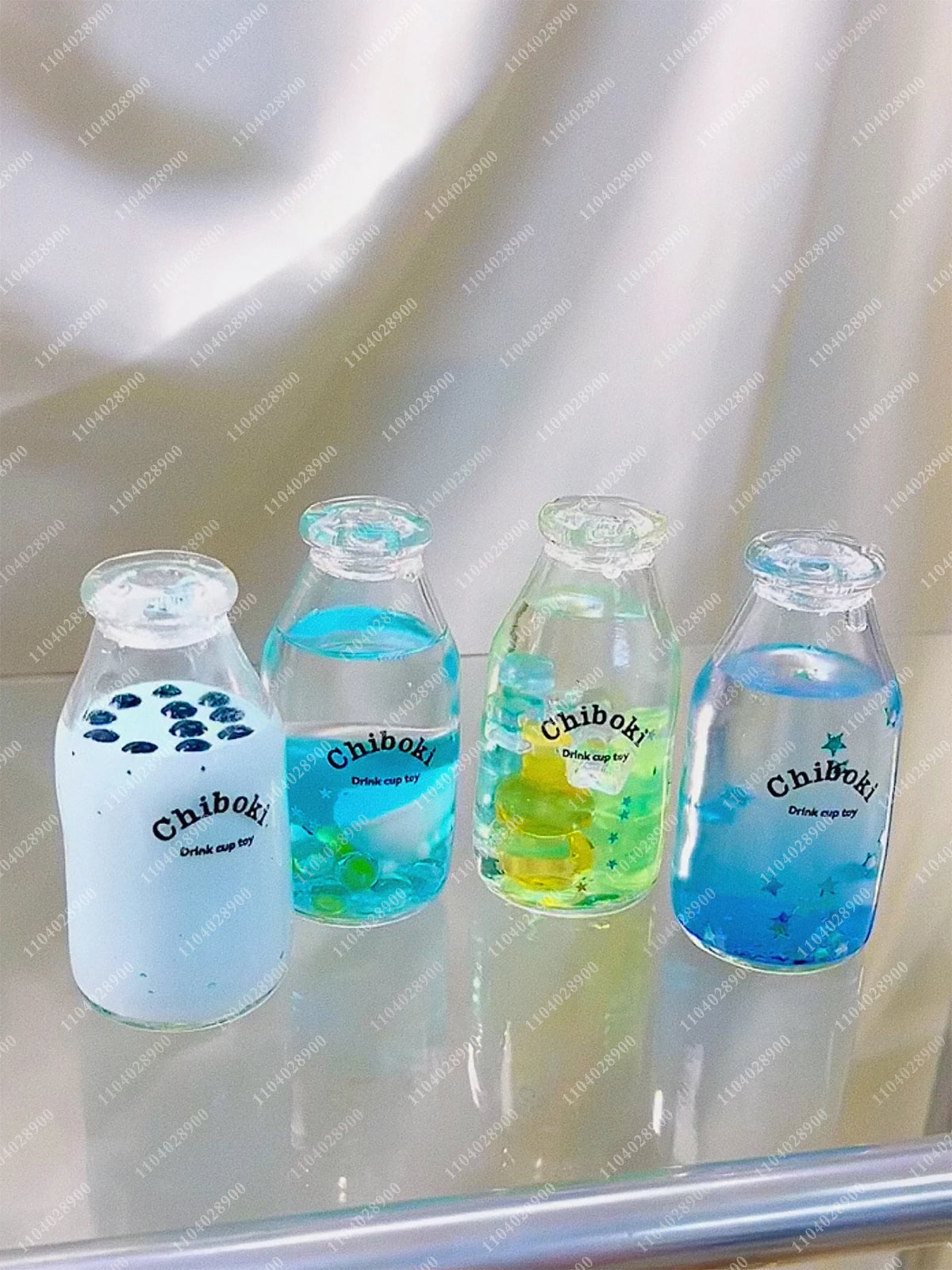 Four clear glass bottles filled with colored liquid labeled Chiboki drink cup for sensory relaxation
