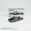 A die-cast model of a Chevrolet Silverado truck in green and orange colors displayed next to its packaging box.
