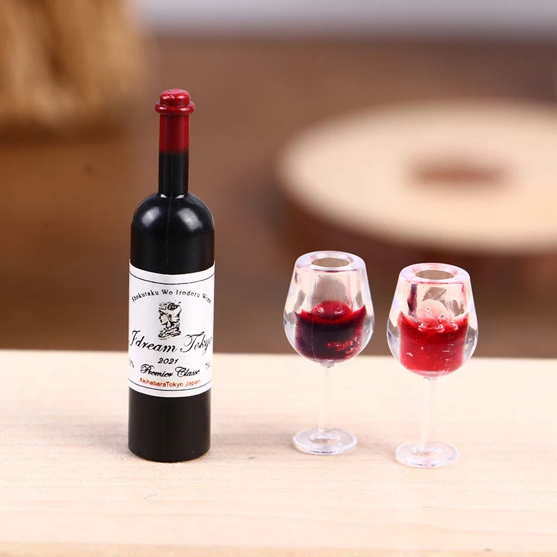 A black miniature resin wine bottle and two corresponding tasting glasses are displayed on a wooden surface.