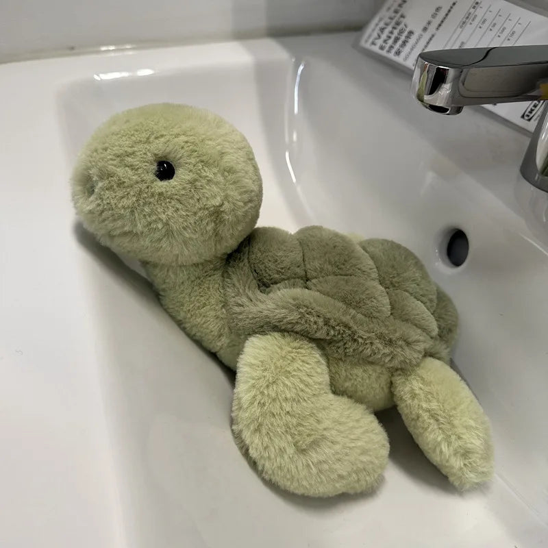 A soft, light green simulated turtle plush doll resting in a white sink.