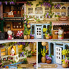 A detailed wooden miniature dollhouse theater kit featuring a storefront with flowers and a balcony.