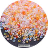 A close-up view of mixed yellow and pink glass seed beads scattered on a dark surface.