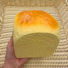 A yellow squishy toy shaped like a loaf of bread with an orange top resting in a woven basket.