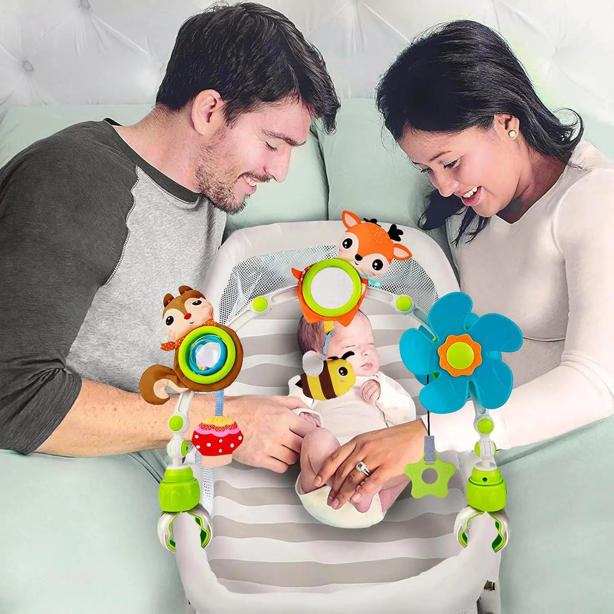 Mutter und Vater interagieren mit einem verstellbaren musikalischen Aktivitätsbogen für Baby-Reisen.