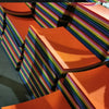 A stack of vibrant orange felt fabric sheets with multicolored stripes, viewed at an angle.