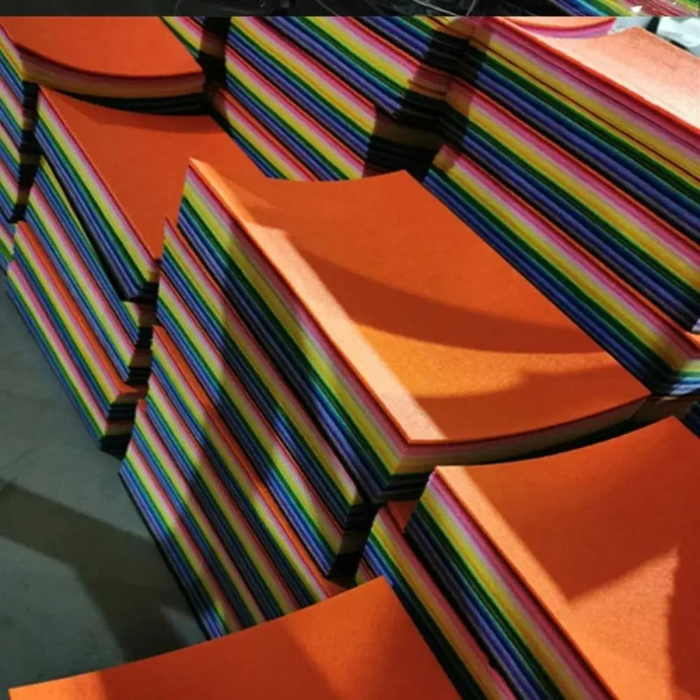 A stack of vibrant orange felt fabric sheets with multicolored stripes, viewed at an angle.