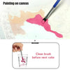 A hand cleans a paintbrush in a glass before applying the next color to a painting on canvas.