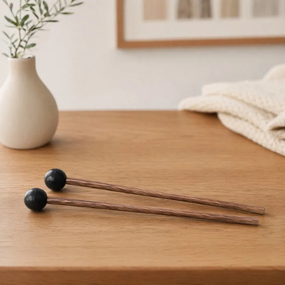 A pair of wooden handpan drum mallets with silicone tips resting on a wooden surface.