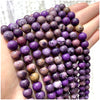 A hand holds a strand of purple and dark stone beads for DIY jewelry making