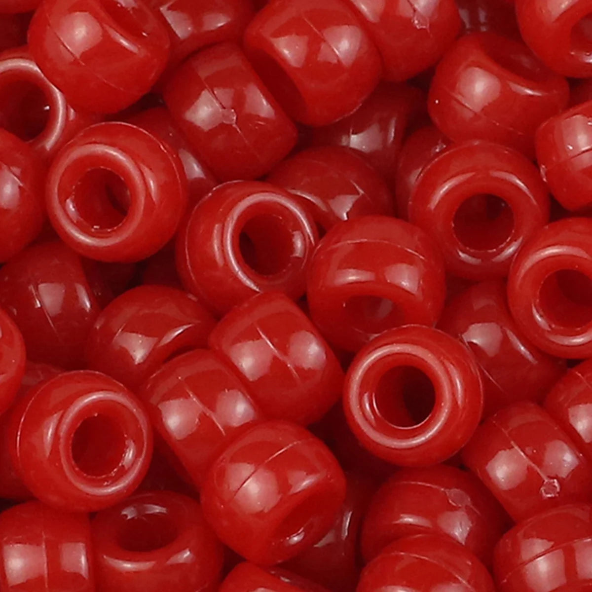 A close-up view of small, glossy red pony beads for jewelry making and craft projects.
