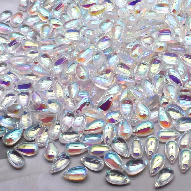 Clear water drop Czech glass beads scattered on a white surface for jewelry making
