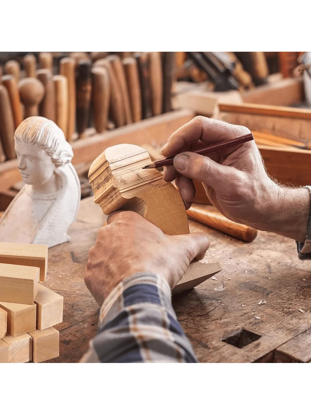 A hand carves a wooden block using a knife in a workshop setting with other wood blocks visible.