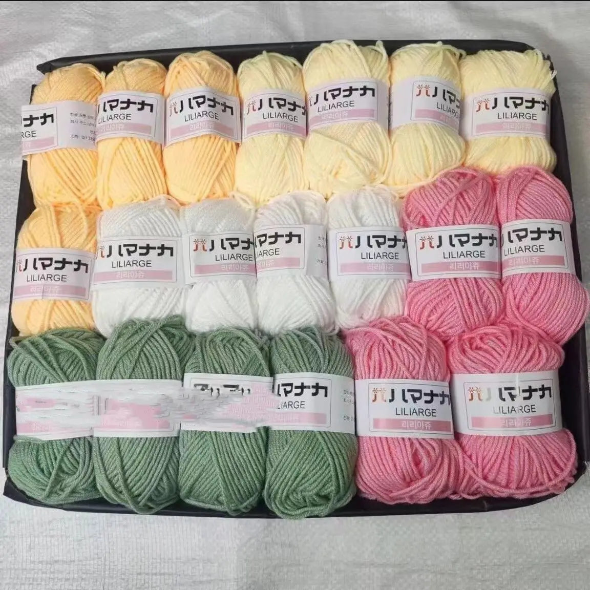 A pack of various colored yarn skeins including yellow, white, pink, and green wool for knitting and crochet projects.