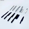 A collection of miniature metal kitchen knives for a dollhouse, including various blade shapes and sizes.