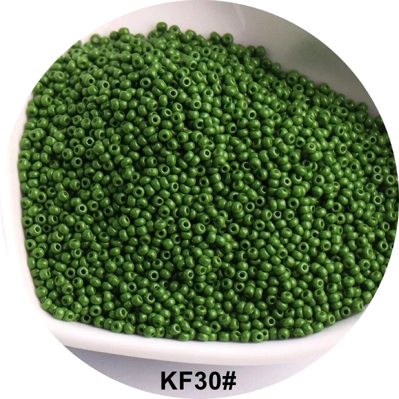 A pile of small, round, green glass seed beads in a white bowl.