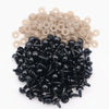 A pile of black plastic safety eyes with washers and a pile of natural beige plastic eyes.