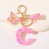 Gold heart keychain with a pink butterfly charm and a pink initial ring.