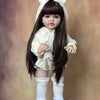 A lifelike 55 cm soft silicone baby doll with long dark hair and white ears wearing a cream outfit.
