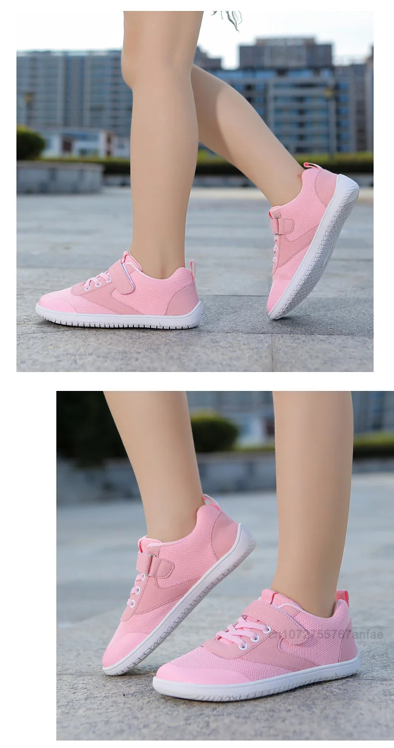 Pink kids barefoot training sneakers shown from the side and top view on a gray outdoor surface.
