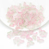 A pile of pink and green butterfly glass beads for jewelry making.