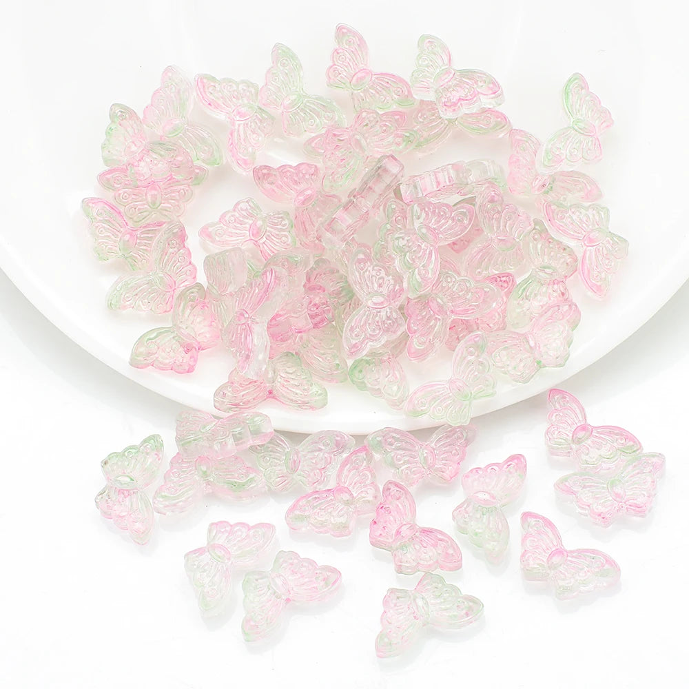 A pile of pink and green butterfly glass beads for jewelry making.