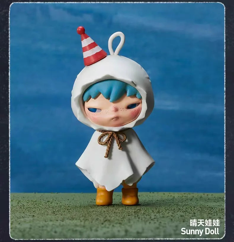 A white hooded doll with blue hair and a striped party hat stands on green grass.