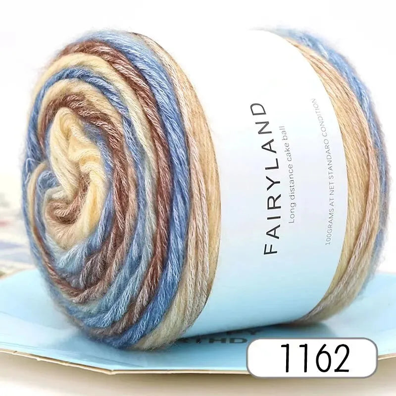 Spool of gradient rainbow yarn showing various shades of blue, brown, and cream.