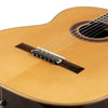 A close-up view of a light brown classical guitar with silver-plated nylon strings stretched across the soundboard.