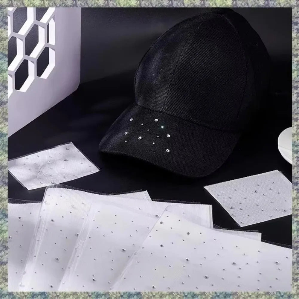 A black baseball cap is shown next to white rhinestone sticker sheets and a white geometric object.