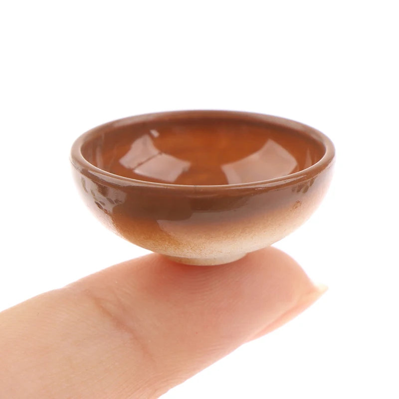 A small, brown ceramic rice bowl is held by a hand against a white background.