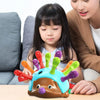 A child is holding a brown hedgehog fine motor skills toy with colorful plastic fingers on a table.