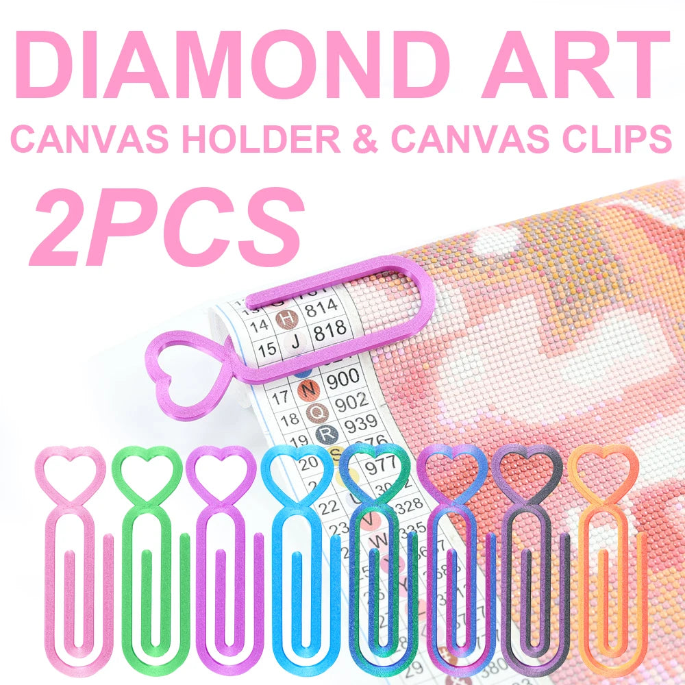 Two heart-shaped canvas clips in various colors pink green blue and orange are shown next to a roll of diamond art canvas.
