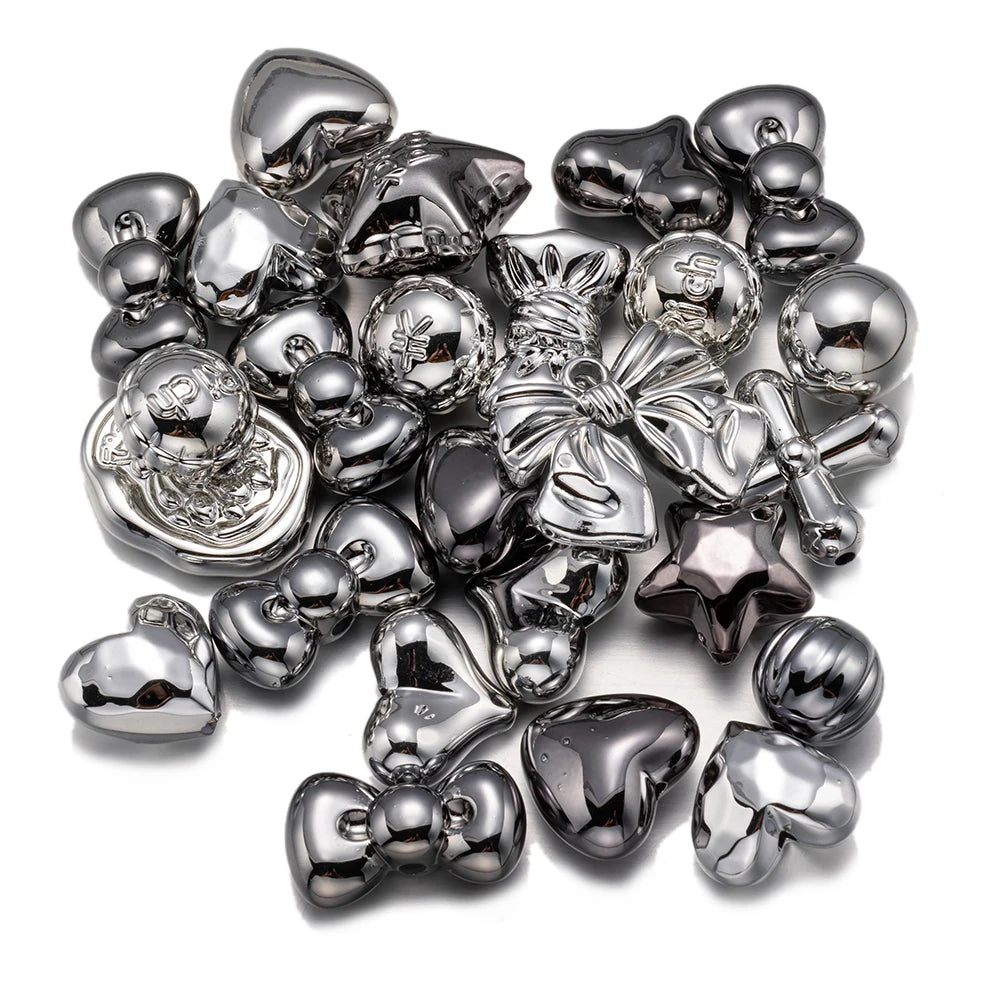 A pile of silver-toned acrylic bow and flower beads for DIY jewelry making.