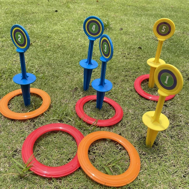 A set of five colored ring toss game components including rings and stakes on a green lawn.