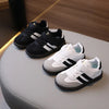 A display of black and white children's PU leather casual sneakers on a light surface.