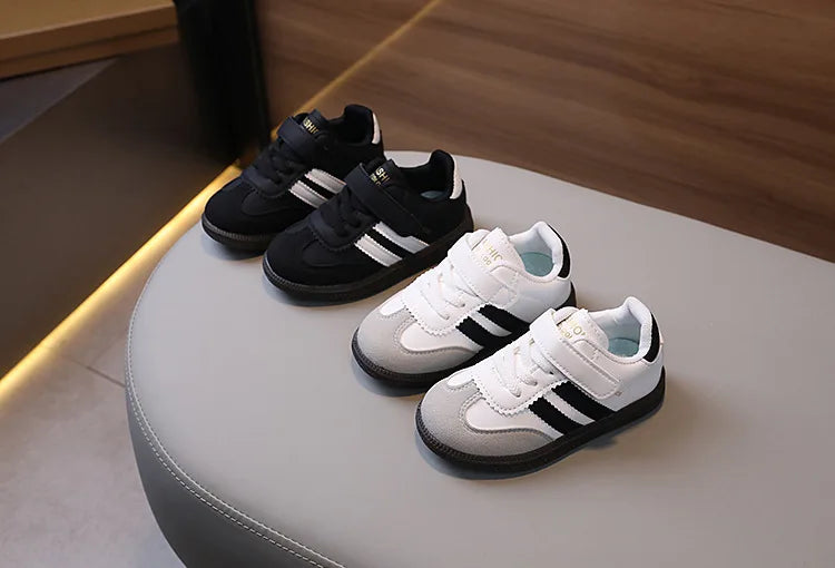 A display of black and white children's PU leather casual sneakers on a light surface.
