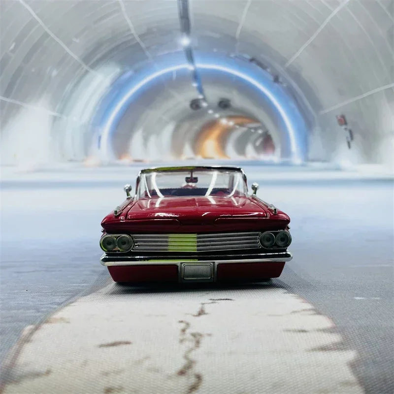 A red vintage 1959 Chevrolet Impala die-cast model car is centered on a gray floor in a futuristic tunnel.