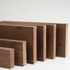 A row of handcrafted black walnut wood boards of varying sizes and thicknesses.