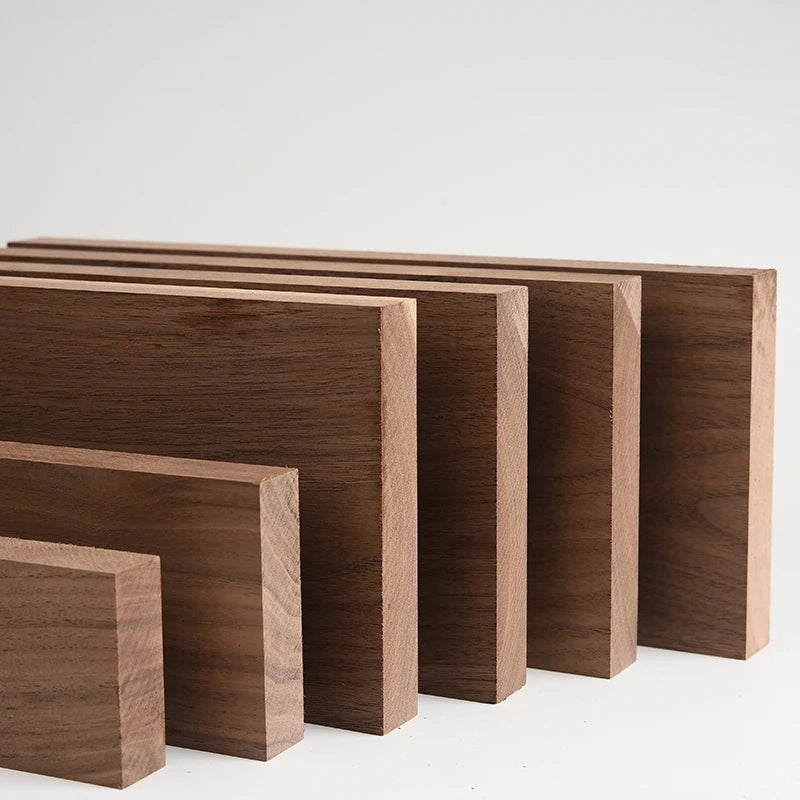 A row of handcrafted black walnut wood boards of varying sizes and thicknesses.