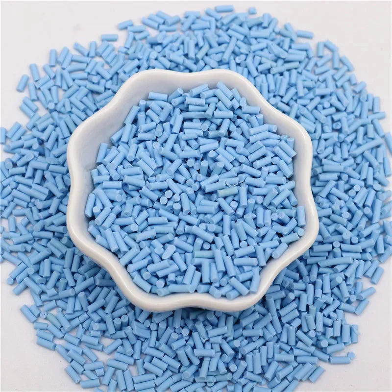 A pile of light blue polymer clay slice sprinkles for slime and DIY crafts in a white dish.