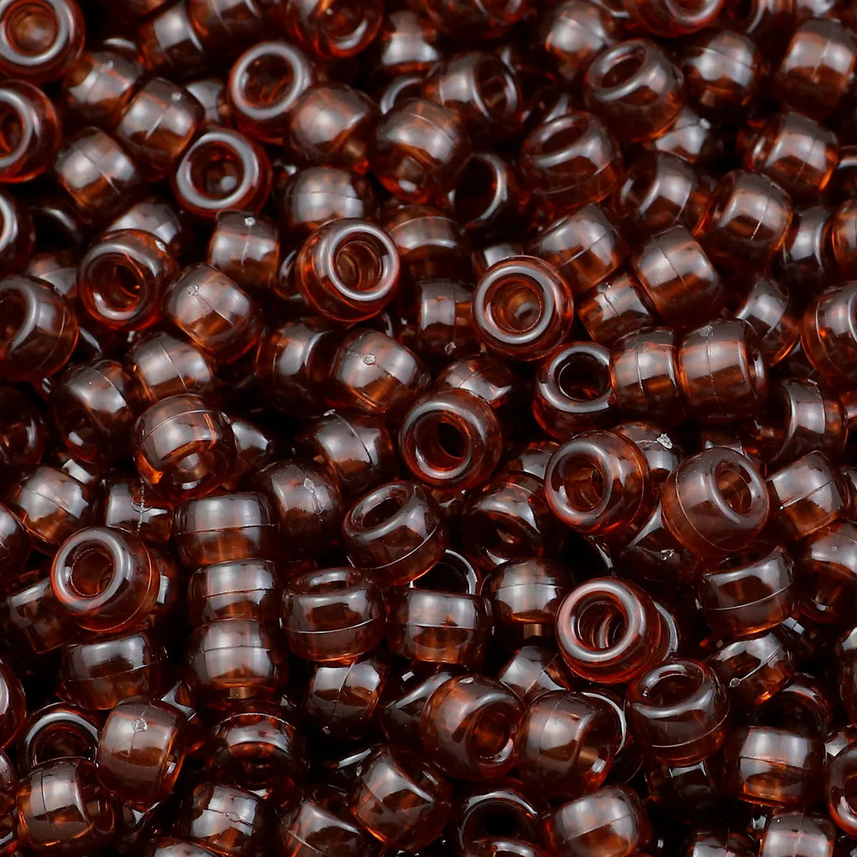A close-up view of small, dark amber pony beads for jewelry making and crafts.