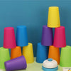 A colorful stacking cups game toy featuring purple, pink, yellow, and blue cups with a bell.