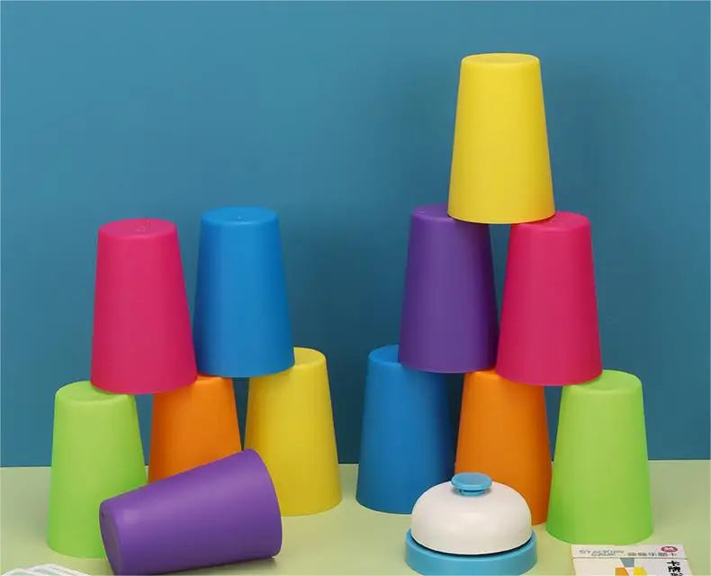 A colorful stacking cups game toy featuring purple, pink, yellow, and blue cups with a bell.