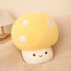 A yellow mushroom plush pillow with white spots and a smiling face resting on a beige textured fabric.