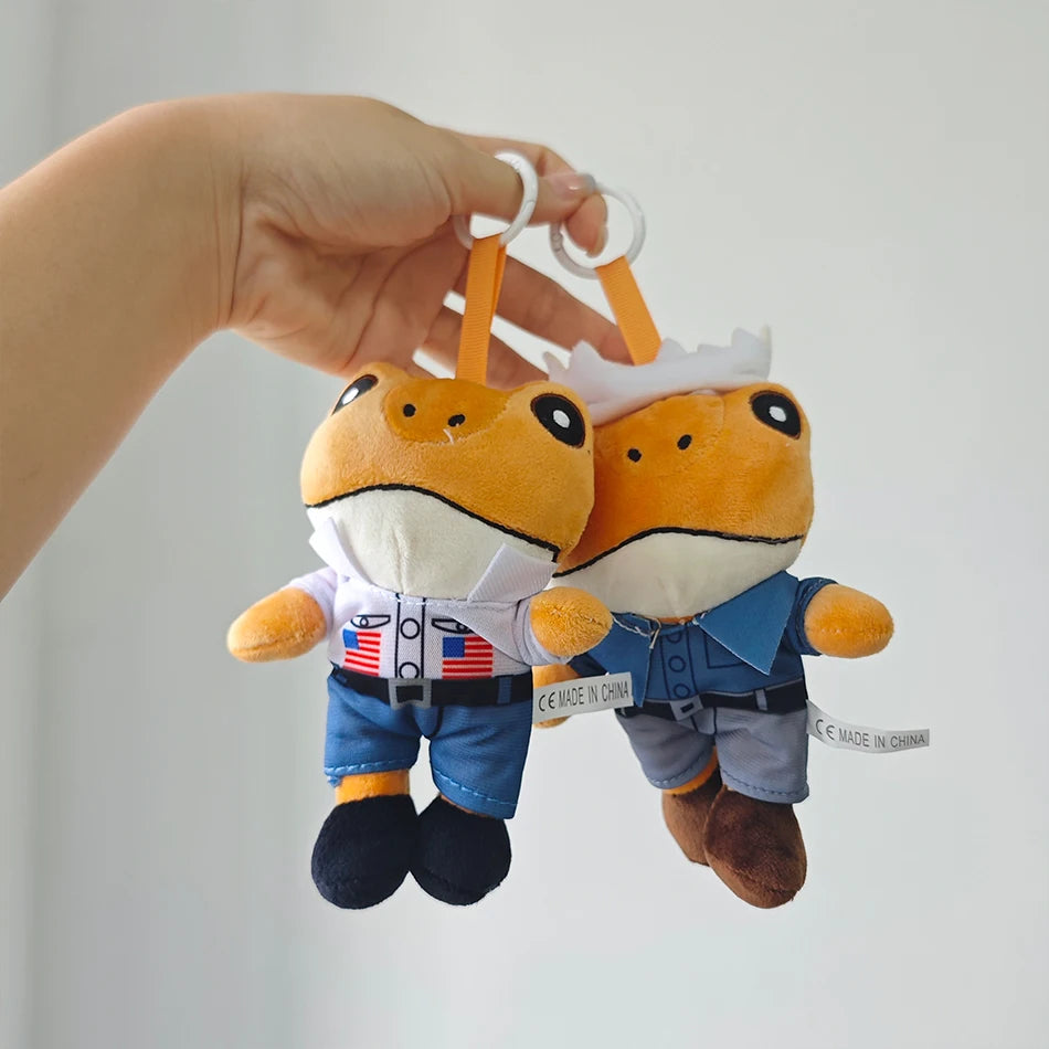 A hand is holding two orange and white plush toys of Bad Bunny El Sapo Concho, featuring patriotic themed outfits.