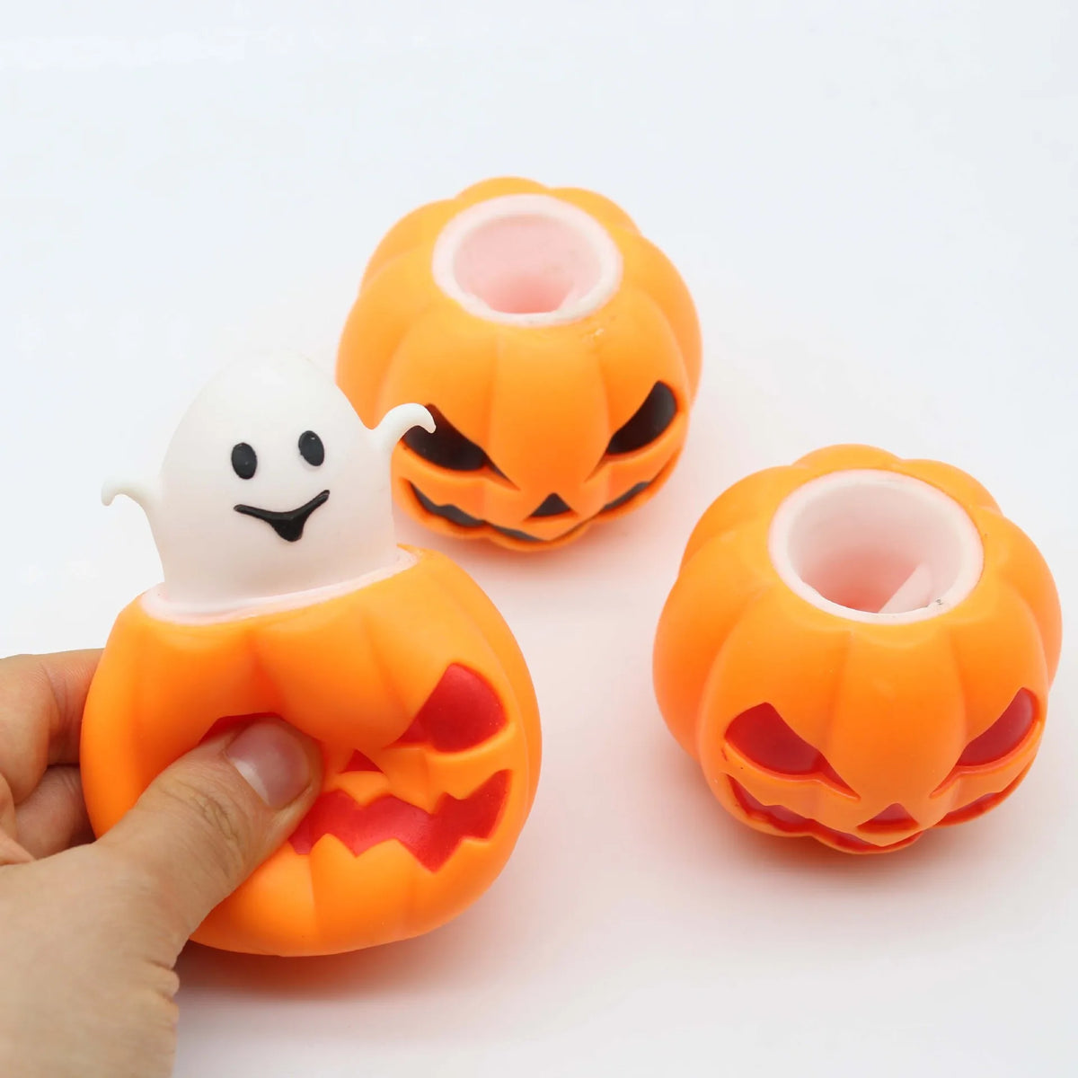 An orange squishy fidget toy shaped like a Halloween pumpkin with a white ghost face and an orange outer shell.